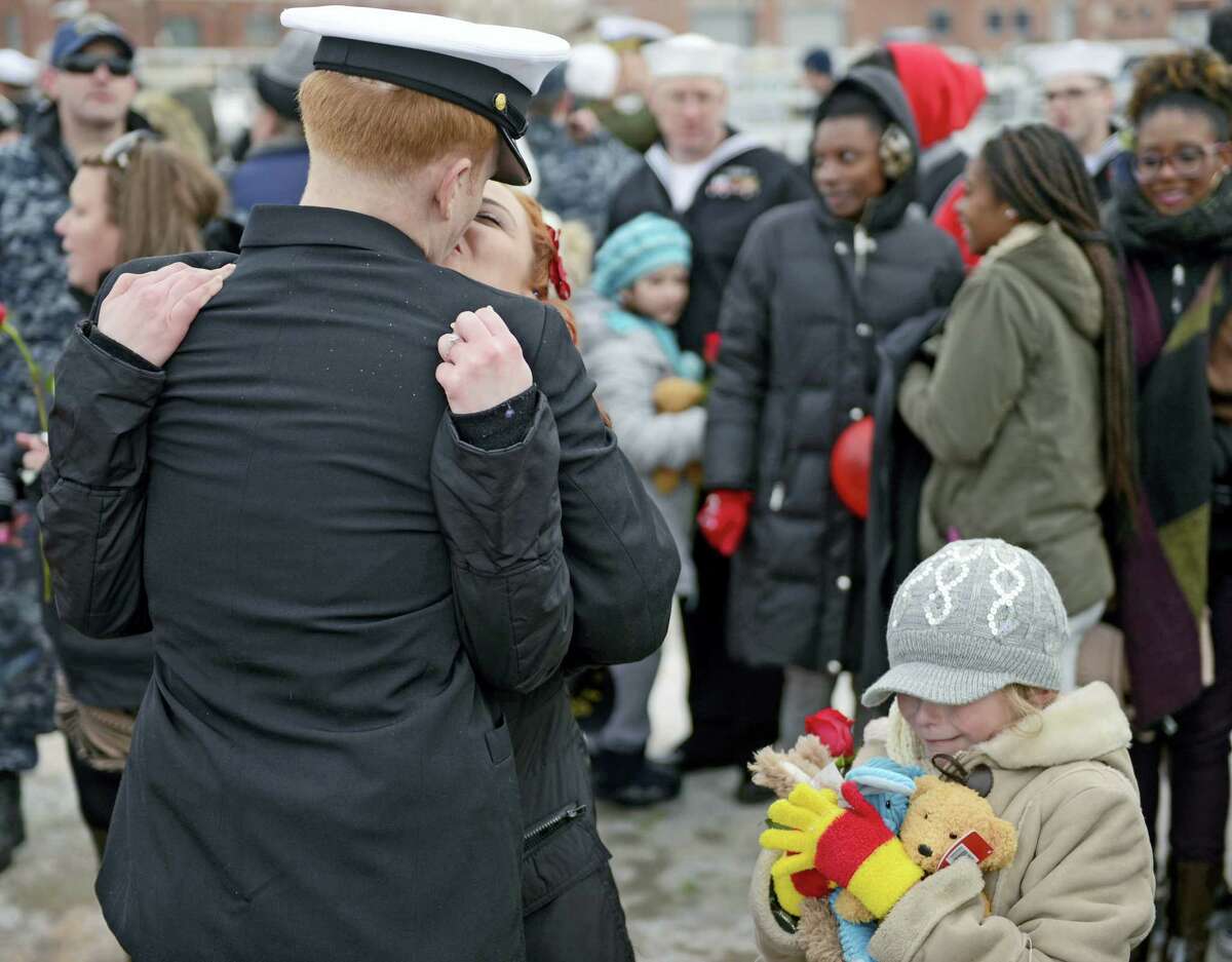 U.S. Navy Chief Petty Officer Chris Jacobson kisses his fiancé Carmen Armstrong as her daughter Evie Armstrong, 8, holds the stuffed animal gifts she received from Jacobson when the navy attack submarine USS Missouri (SSN 780) returned to the Navy Submarine Bast in Groton, Conn., Friday, Feb. 12, 2016 following a six-month deployment to the European Command area of responsibility. The Missouri, the seventh sub in the Virginia-class, made port calls in Faslane, Scotland, Rota, Spain and Brest, France during the deployment.