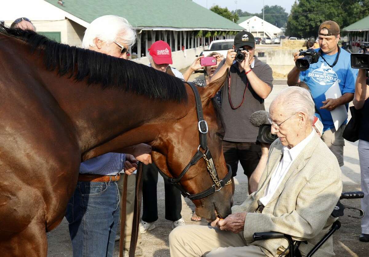 Longtime veterinarian Dr. William McGee, 98, who has treated several Triple Crown winners, feeds a carrot 2015 Triple Crowner American Pharoah at Churchill Downs, on Friday.
