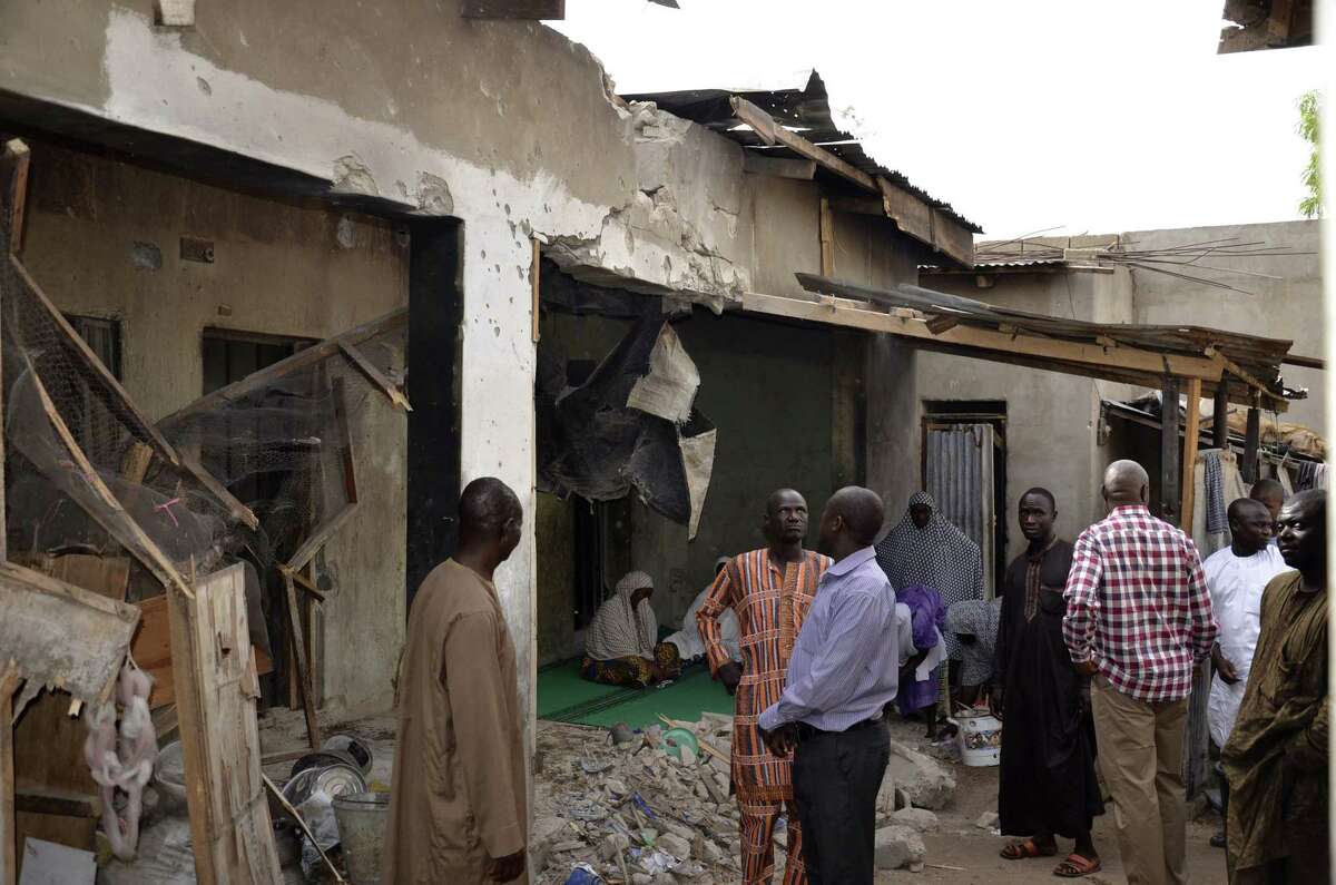 People inspect houses damaged damaged in Saturday's rocket propelled grenades by Islamic extremist in Maiduguri, Nigeria, Sunday, May 31, 2015. A bomb injured four people in a market Sunday in Maiduguri, a day after the northeastern Nigerian city was hit by a suicide bomber who killed 16 in a mosque. (AP Photo/Jossy Ola)