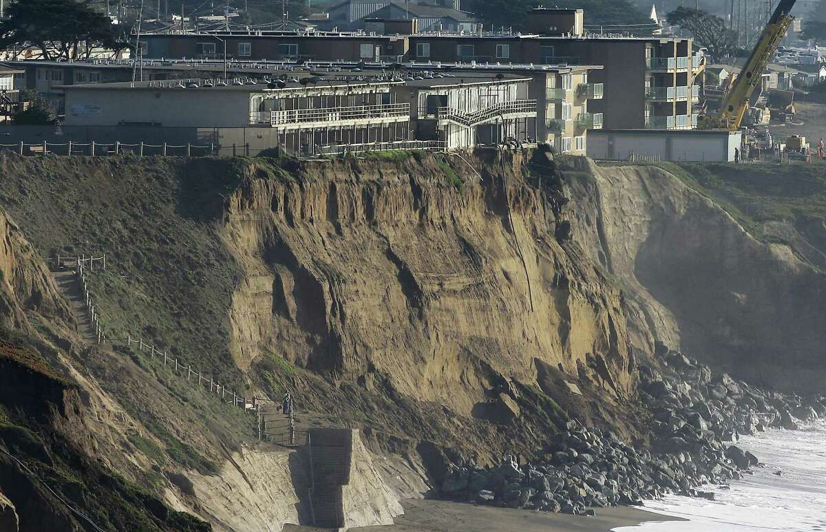 In this Jan. 27, 2016, file photo, boulders shore up an eroding cliff below an apartment complex that residents were forced to evacuate, at top left, in Pacifica, Calif. Living with the Pacific Ocean as your backyard has its benefits. But the crumbling ocean cliffs have forced dozens to move quickly and at a high cost.