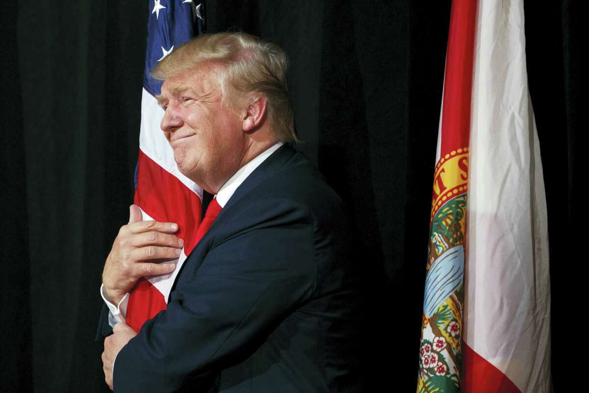 Republican presidential candidate Donald Trump hugs a the American flag as he arrives to speak to a campaign rally on Oct. 24, 2016 in Tampa, Fla.