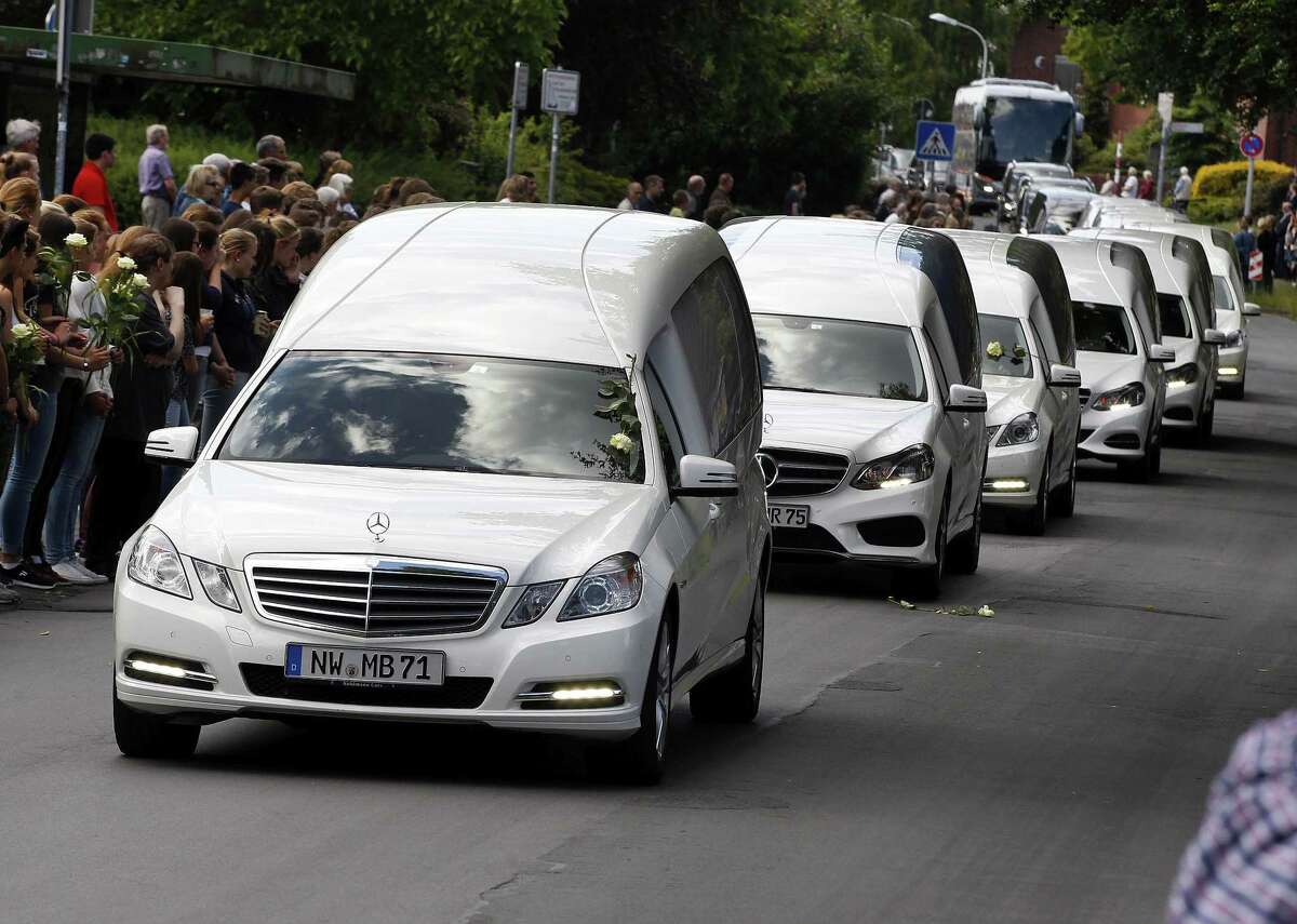 White hearses carrying the remains of pupils killed in the Germanwings plane crash in France are about to pass by the Joseph-Koenig high school in Haltern, Germany, Wednesday, June 10, 2015. 150 people died in the plane crash on March 24. (AP Photo/Michael Probst)
