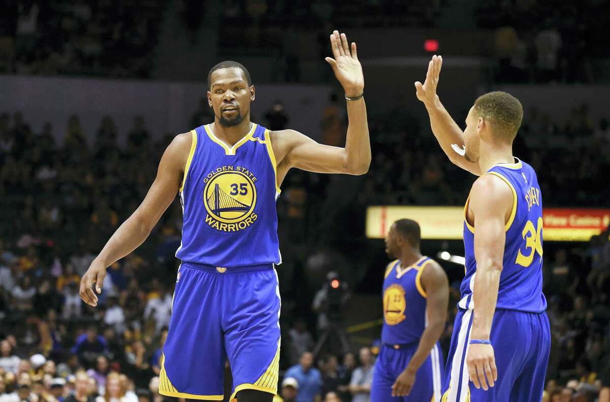 Golden State Warriors forward Kevin Durant, left, high-fives Stephen Curry during a preseason game.