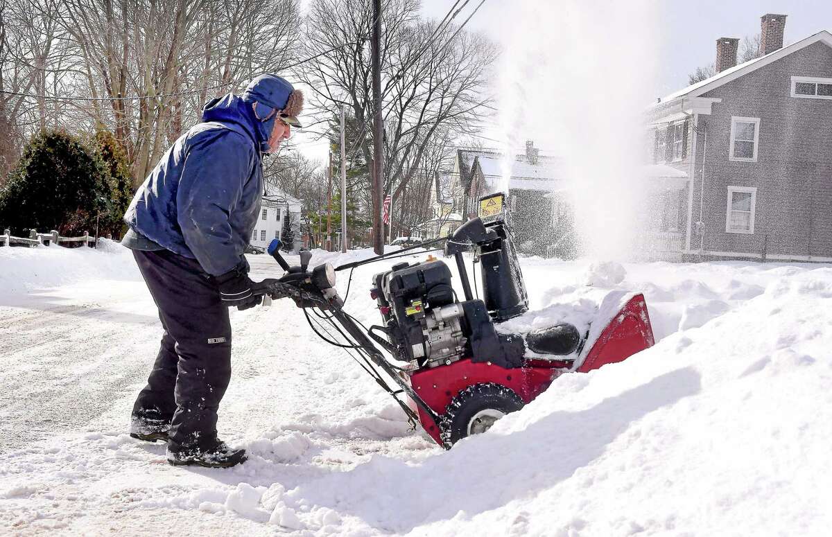 Jesus Barrera clears snow from in front of a home on West River Street in Milford earlier this month.