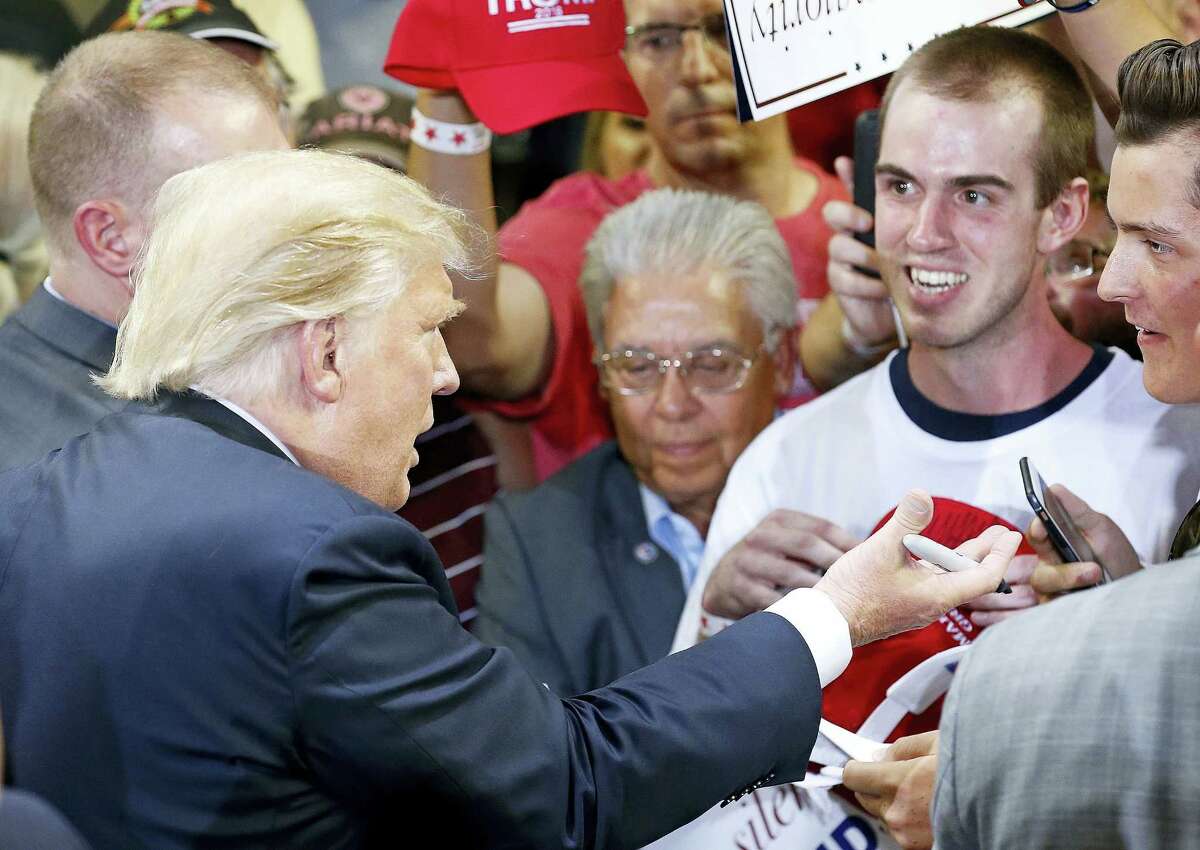 Republican presidential candidate Donald Trump talks to supporters as he signs autographs after speaking at a rally Saturday in Phoenix.