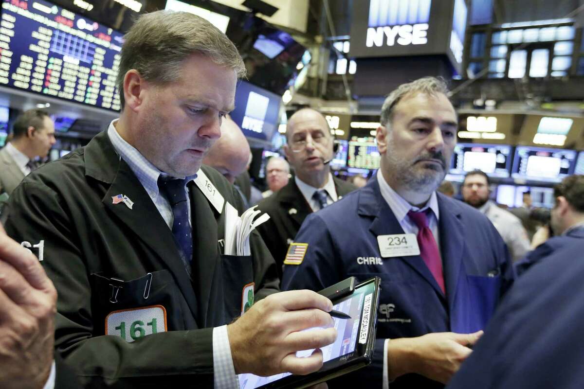 Thomas McCauley, left, works with fellow traders on the floor of the New York Stock Exchange Monday.