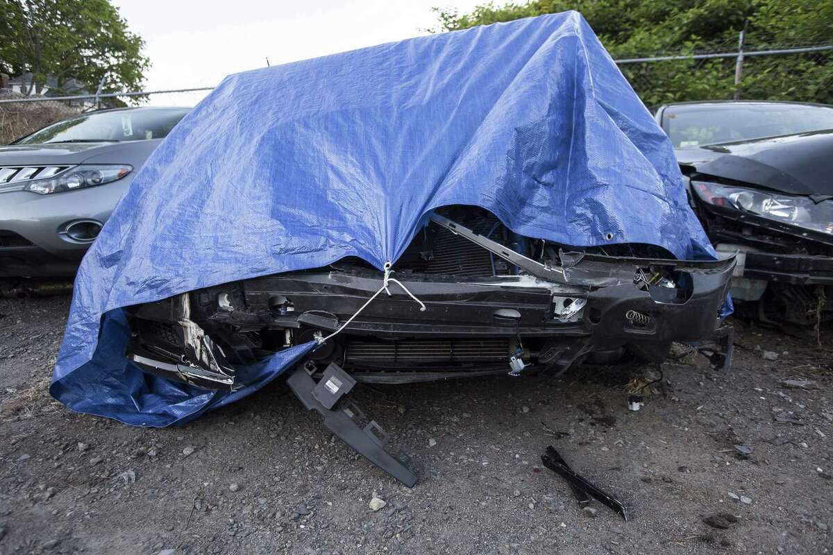 The damaged Mercedes-Maybach belonging to former New England Patriots linebacker Brandon Spikes is covered with a tarp in a tow yard in North Attleborough, Mass.