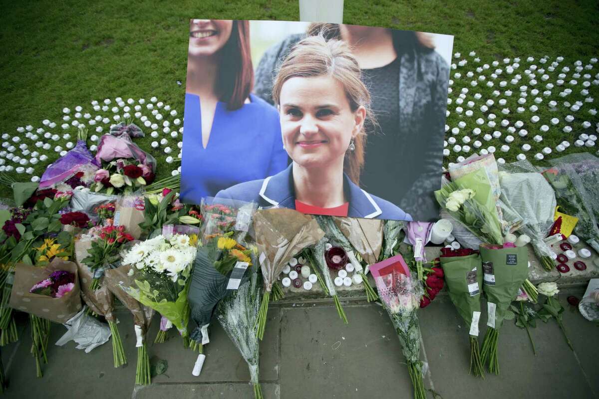 An image and floral tributes for Jo Cox, lay on Parliament Square, outside the House of Parliament in London, Friday, June 17, 2016, after the 41-year-old British Member of Parliament was fatally injured Thursday in northern England. The mother of two young children was shot to death Thursday afternoon in her constituency near Leeds. A 52-year-old man has been arrested but has not been charged. He has been named locally as Tommy Mair.