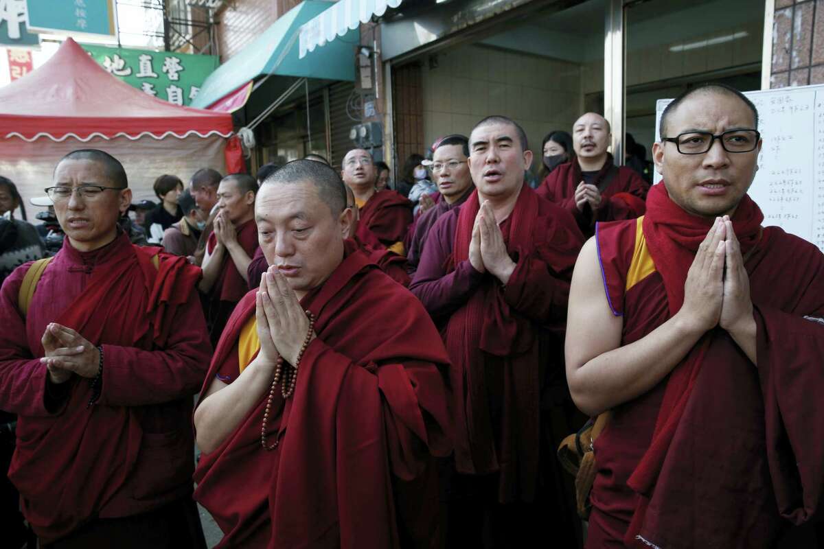 Tibetan monks pray for the missing persons said to be still inside the collapsed building complex in Tainan, Taiwan on Feb. 7, 2016.