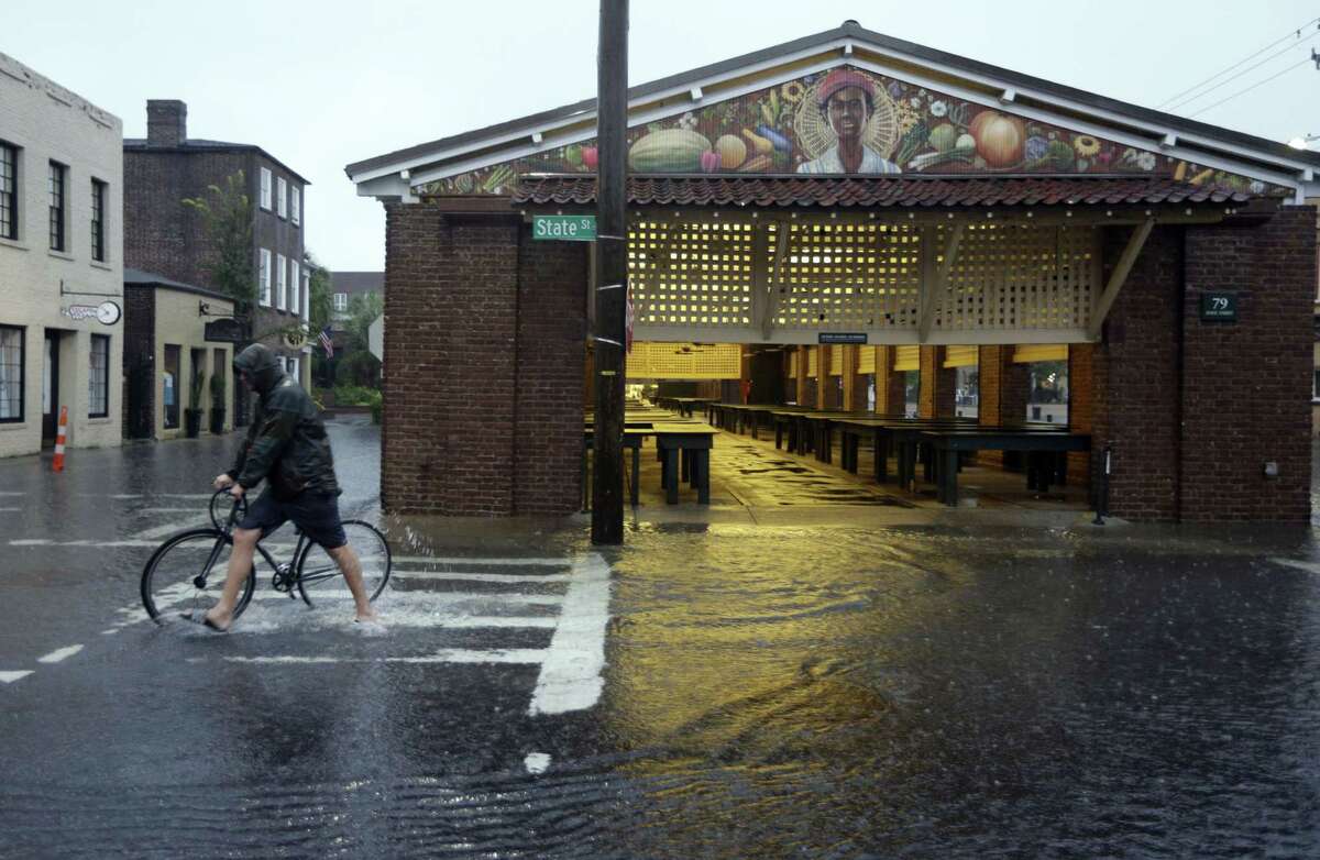 A man walks his bicycle through high water at the City Market in downtown Charleston, S.C., Saturday, Oct. 3, 2015. The National Weather Service says the risk of flooding will continue through Monday morning, especially in parts of North and South Carolina that already have gotten up to 11 inches of rain this week. Forecasters say some areas could see storm totals as high as 15 inches.