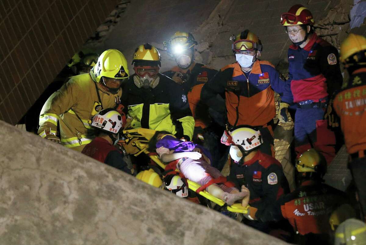 A female is rescued from a collapsed building complex after an early morning earthquake in Tainan, Taiwan, Saturday, Feb. 6, 2016. A 6.4-magnitude earthquake struck southern Taiwan early Saturday, toppling at least one high-rise residential building and trapping people inside.
