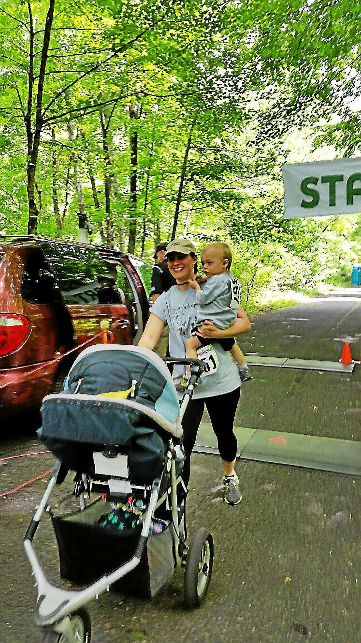 Heather Huebner of Derby came in the finish line while carrying her son Dorian, 2, during Saturday afternoon’s second annual Wheels and Heels 5K Road Race on Valley Road in Harwinton.