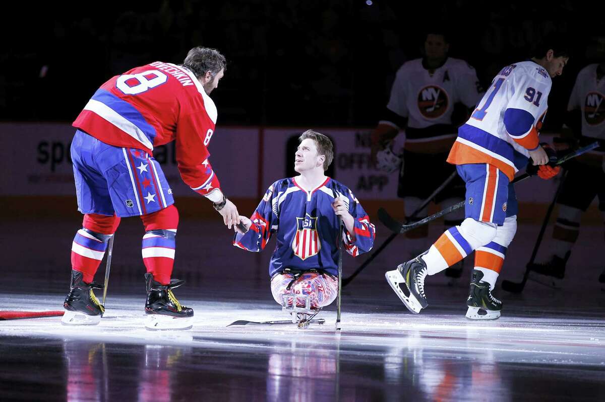 US Marine Corps Lance Corporal Joshua Misiewicz, a member of the USA National sled hockey team, gets a puck from Washington Capitals left wing Alex Ovechkin (8), from Russia, after a pre-game ceremonial puck drop with New York Islanders center John Tavares (91) before an NHL hockey game, Thursday, Feb. 4, 2016, in Washington. (AP Photo/Alex Brandon)