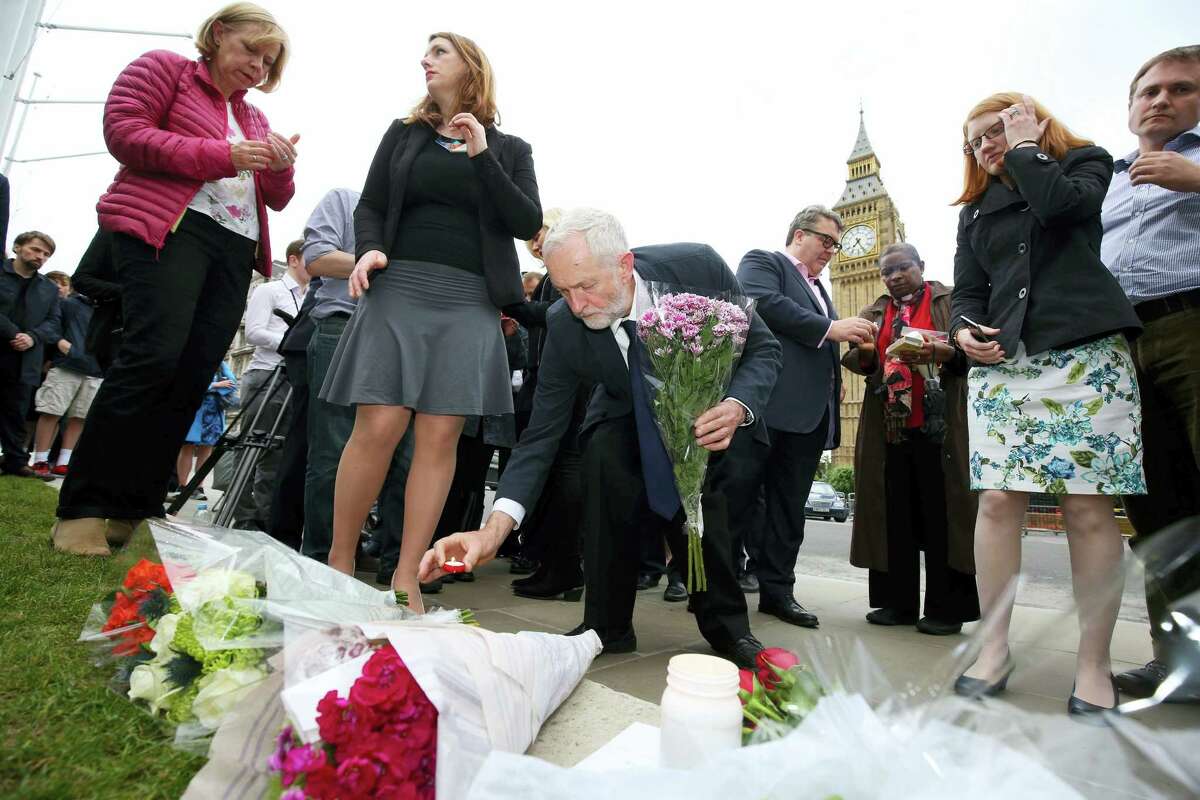 Labour Party leader Jeremy Corbyn, center, lays a candle as he and deputy leader Tom Watson, centre rear, Thursday June 16, 2016, attend an impromptu vigil at Parliament Square opposite the Palace of Westminster, central London, following the death of Labour Member of Parliament, Jo Cox. The British lawmaker who campaigned for the country to stay in the European Union was killed Thursday by a gun- and knife-wielding attacker in her small-town constituency, a tragedy that brought the country’s fierce, divisive referendum campaign to a shocked standstill.