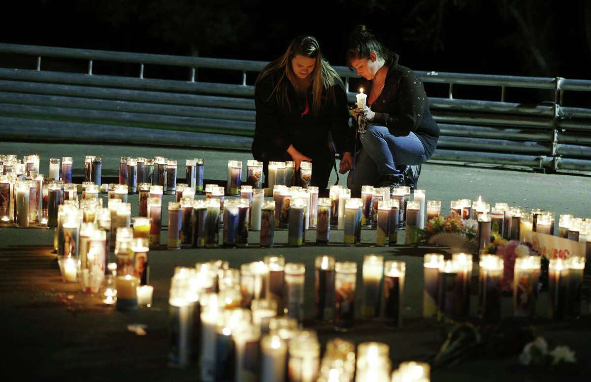 Meriah Calvert, left, of Roseburg, Ore., and an unidentified woman pray by candles spelling out the initials for Umpqua Community College after a candlelight vigil Thursday in Roseburg, Ore.