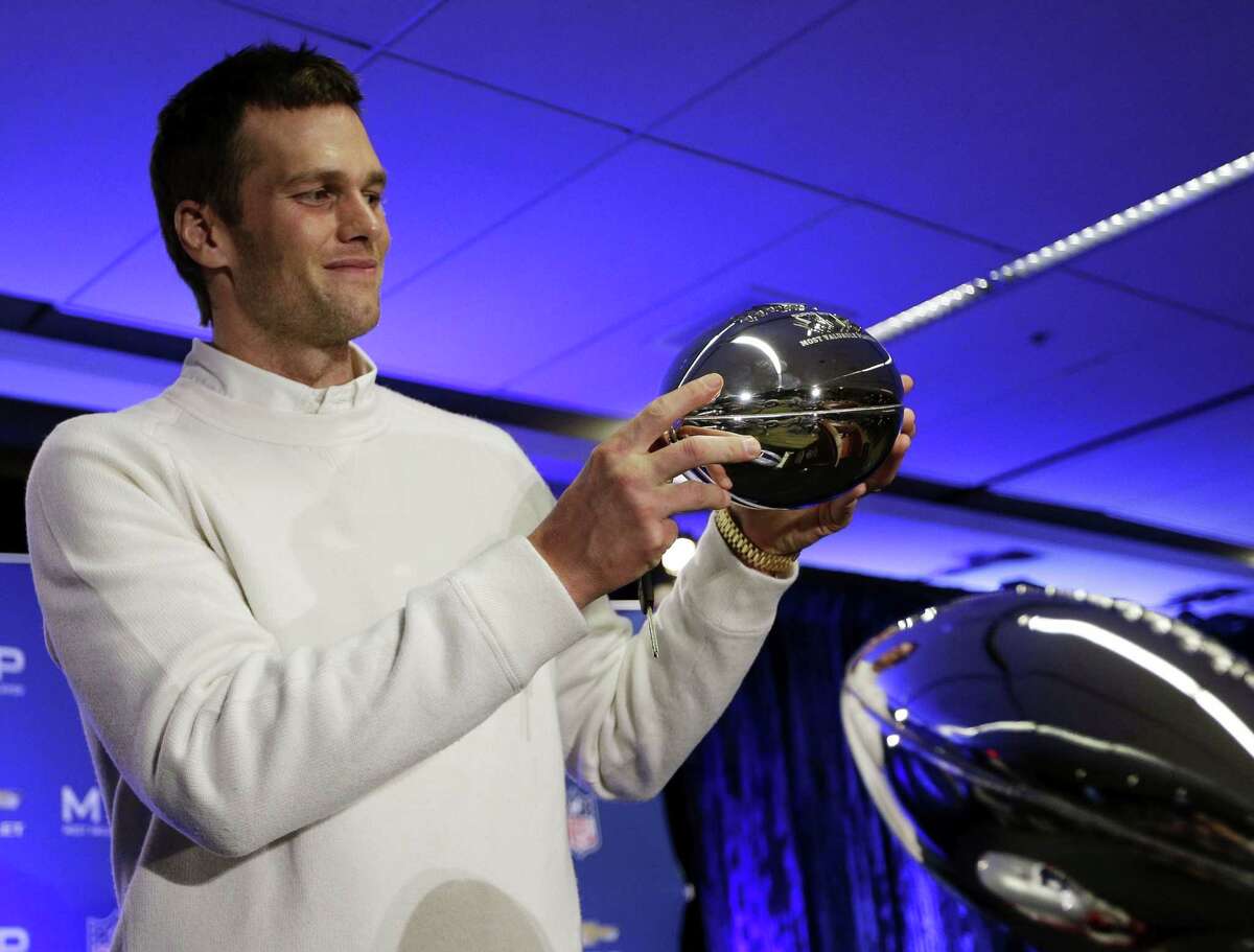 New England Patriots quarterback Tom Brady holds up his Pete Rozelle Trophy during a news conference.