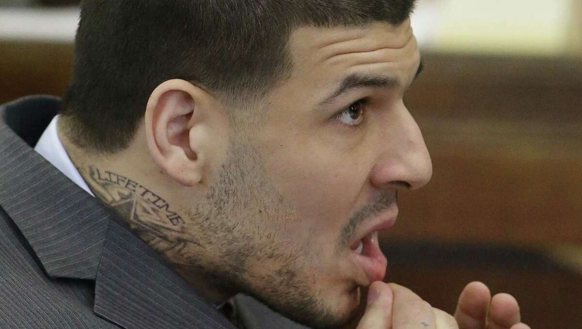 Sporting a new neck tattoo former New England Patriots NFL football player Aaron Hernandez sits at the defense table during his arraignment on a charge of trying to silence a witness in a double murder case against him by shooting the man in the face at Suffolk Superior Court Thursday, May 21, 2015, in Boston. (AP Photo/Stephan Savoia, Pool)