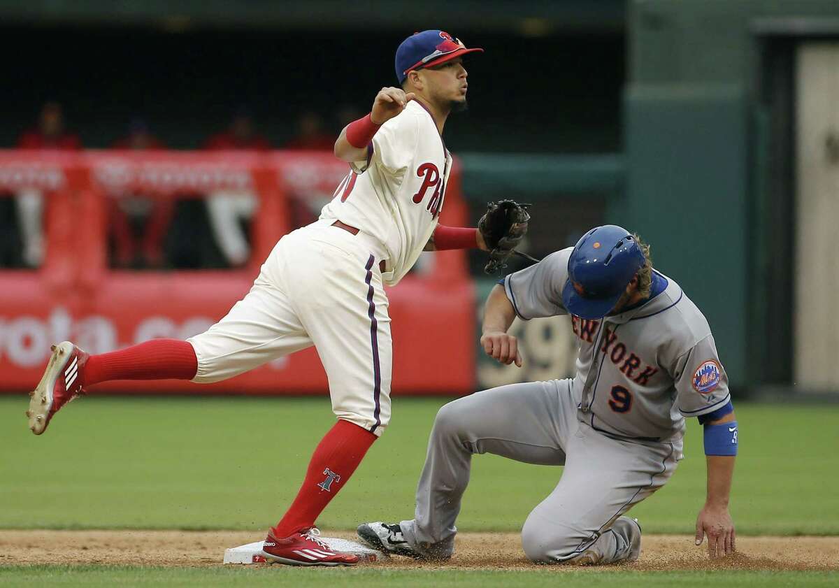 Phillies shortstop Freddy Galvis, left, watches his throw to first base after forcing out the Mets’ Kirk Nieuwenhuis at second base on a double play on Thursday.