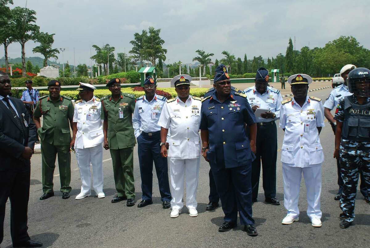 FILE - In this Monday, May. 26, 2014 file photo, Nigeria's chief of defense staff Air Marshal Alex S. Badeh, foreground third right, and other military chiefs wait to address the Nigerians Against Terrorism group during a demonstration calling on the government to rescue the kidnapped girls of the government secondary school Chibok, in Abuja, Nigeria. Nigerian military abuses caused the deaths of some 8,000 people in the fight against Boko Haram extremists, Amnesty International said Wednesday, June. 3, 2015 in a report naming senior officers it wants investigated for alleged war crimes. (AP Photo/Olamikan Gbemiga File)