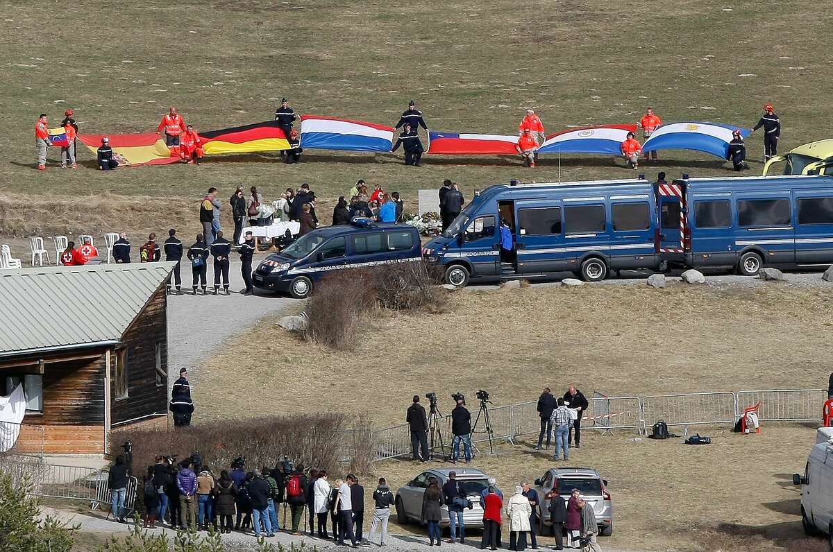 Flags representing differents nations are deployed during ceremony with family members of victims in front of a stele, a stone slab erected as a monument, set up in memory of the victims in the area where the Germanwings jetliner crashed in the French Alps, in Le Vernet, France, Sunday.