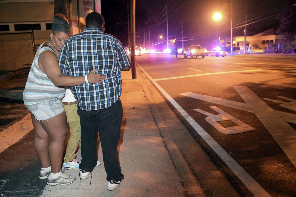 Bystanders wait down the street from a multiple shooting at the Pulse nightclub in Orlando, Fla. on June 12, 2016. A gunman opened fire at a nightclub in central Florida, and multiple people have been wounded, police said Sunday.