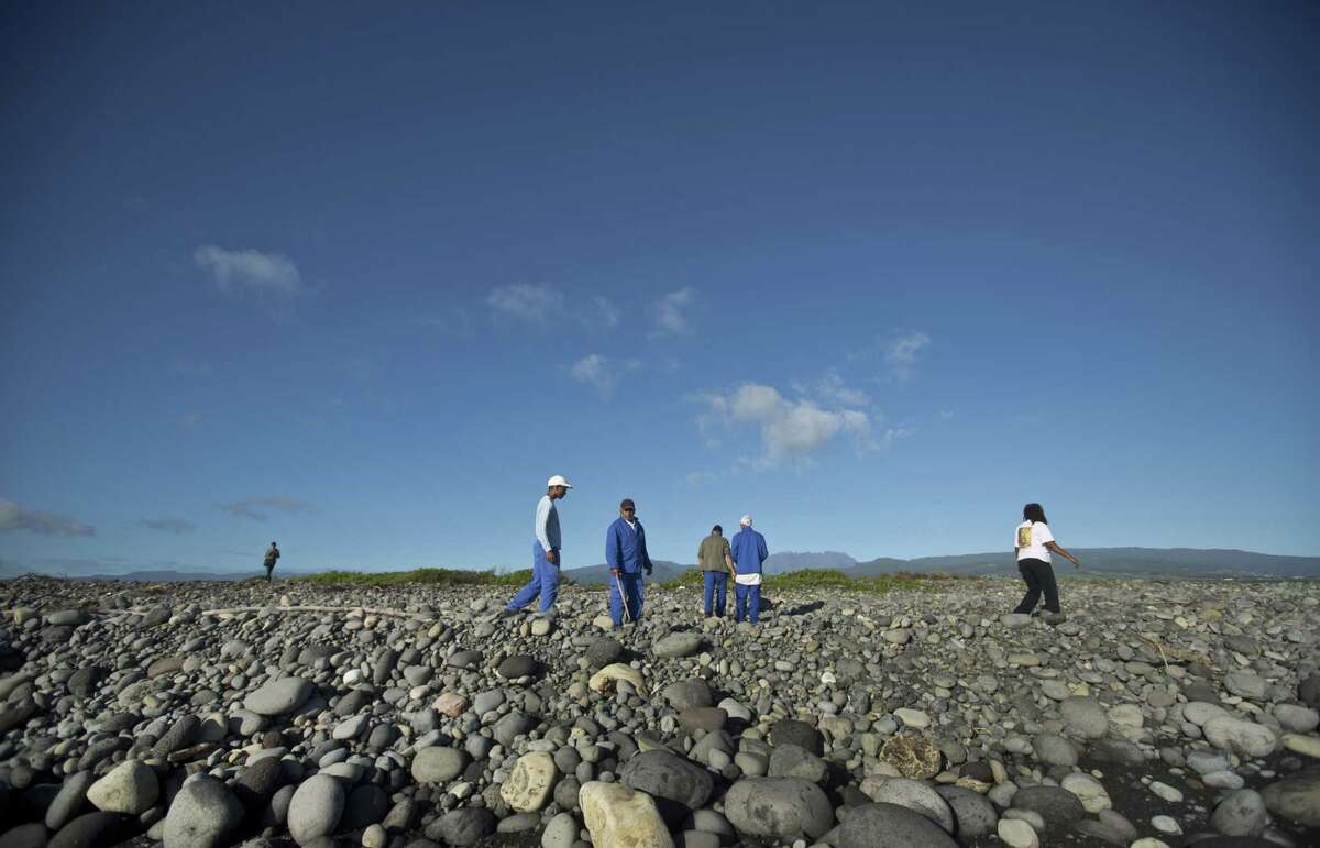 Workers for an association responsible for maintaining paths to the beaches from being overgrown by shrubs, search the beach for possible additional airplane debris near the area where an airplane wing part was washed up, in the early morning near to Saint-Andre on the north coast of the Indian Ocean island of Reunion Friday.