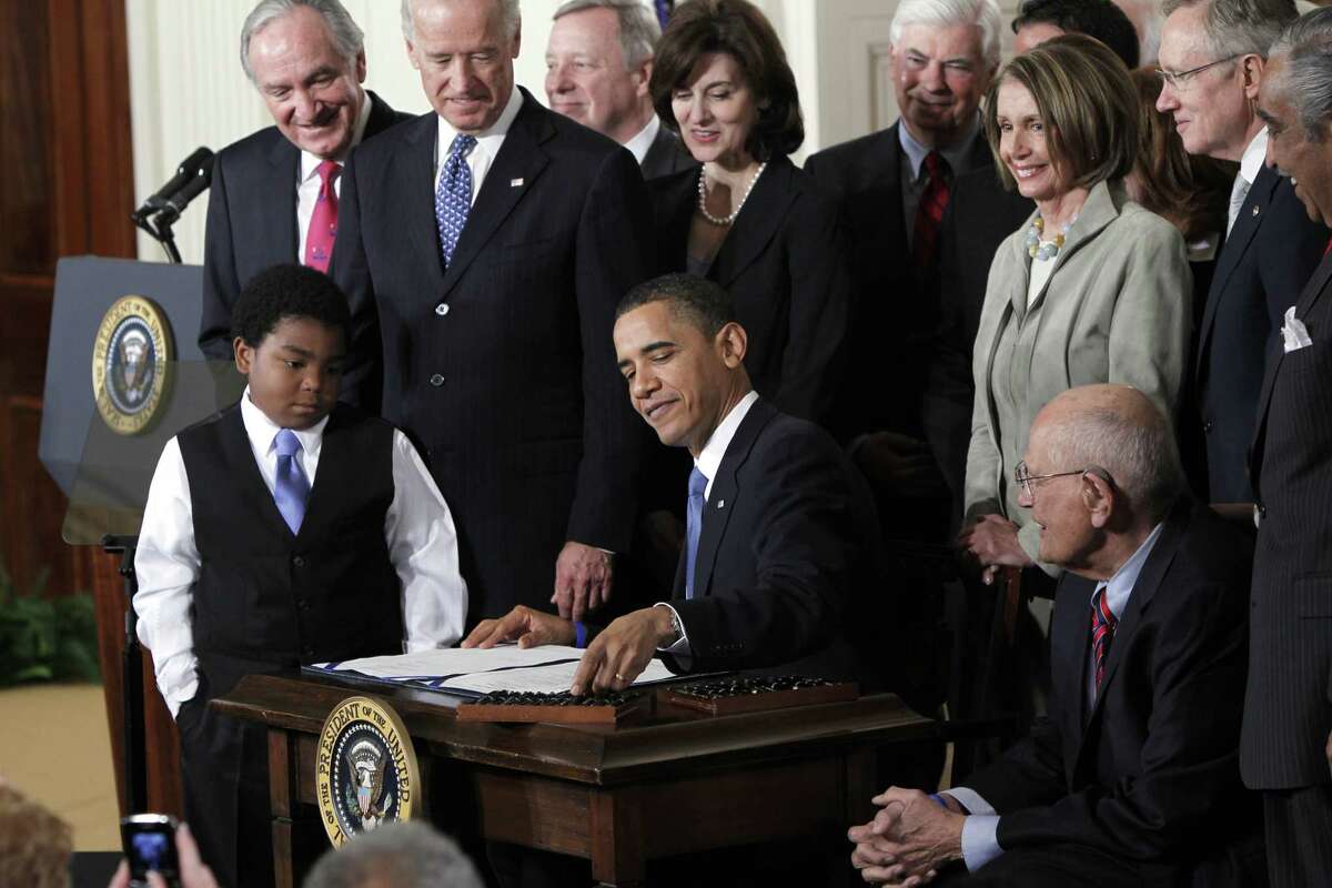In this March 23, 2010, file photo, President Barack Obama reaches for a pen to sign the health care bill in the East Room of the White House in Washington. Nonprofit co-ops, the health care law’s public-spirited alternative to mega insurers, are awash in red ink and many have fallen short of sign-up goals, a government audit has found.