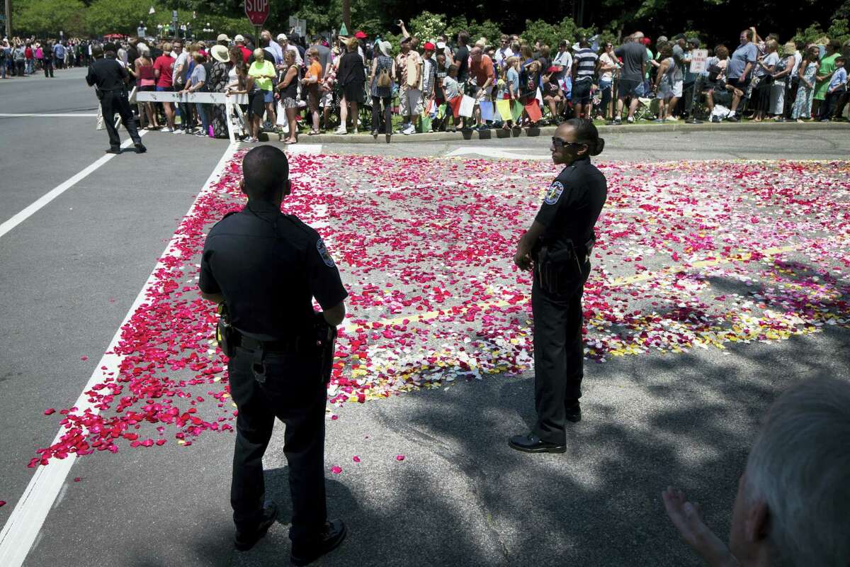 Police stand guard along a rose petal-covered entrance way to Cave Hill Cemetery before the arrival of Muhammad Ali’s funeral procession, Friday, June 10, 2016, in Louisville, Ky. Ali’s body rode in a miles-long procession spanning his life — from his boyhood home where he shadowboxed and dreamed of greatness to the boulevard that bears his name and the museum that stands as a lasting tribute to his boxing triumphs and his humanitarian causes outside the ring. Ali died last Friday at 74 after a long battle with Parkinson’s disease.