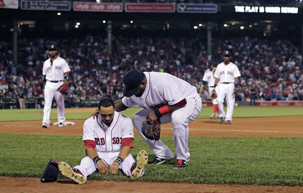 Boston Red Sox center fielder Mookie Betts sits on the infield as teammate Pablo Sandoval checks to see if he’s injured following a play where Betts flipped over the bullpen wall while trying to catch a drive by Chicago White Sox’s Jose Abreu during the sixth inning of a baseball game at Fenway Park in Boston, Tuesday, July 28, 2015. Betts left the game after the play.