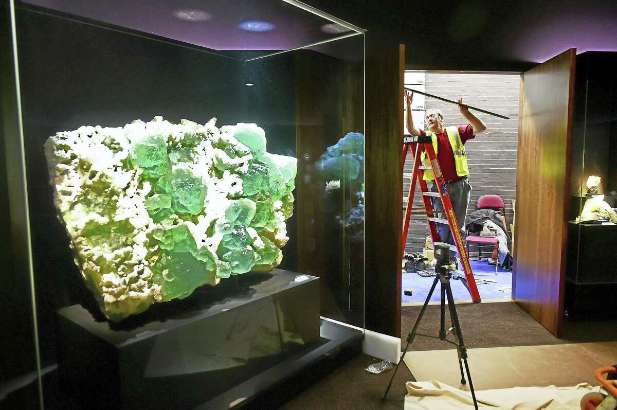 Carpenter Martin Belas adds some finishing touches to the construction of the Yale Peabody Museum of Natural History’s new David Friend Hall. At left is a 4,000-pound lime-green fluorite with quartz.