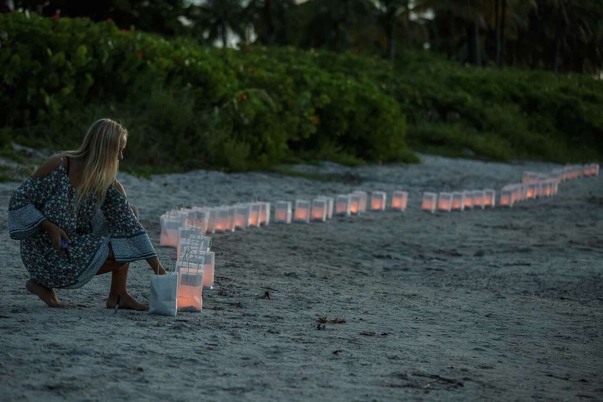 Lilly Folds lights paper lanterns during a candlelight vigil and paper balloon release at Jupiter Inlet Park Monday for teenagers Austin Stephanos and Perry Cohen in Jupiter, Fla. The teens were last seen Friday afternoon buying fuel near Jupiter and were believed to have been heading toward the Bahamas.