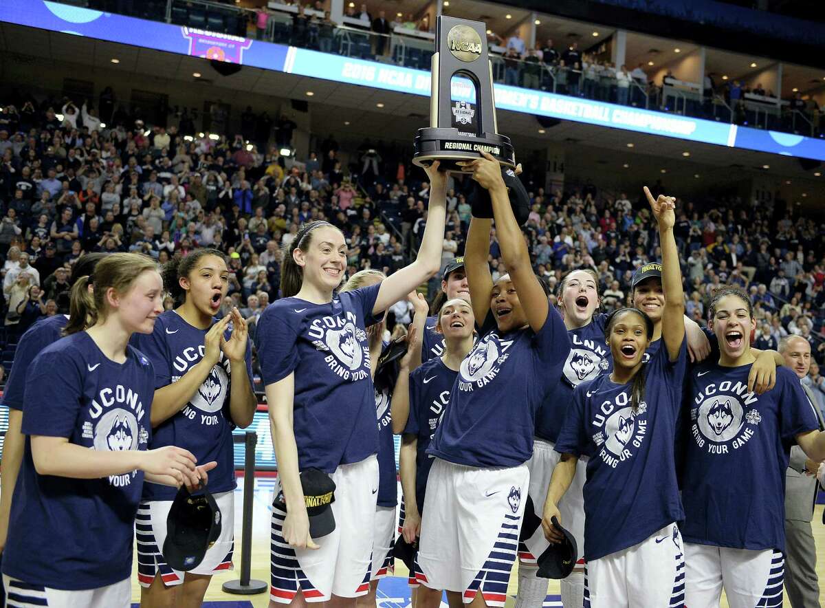 UConn’s Breanna Stewart, left, and Morgan Tuck celebrate with the trophy and teammates after defeating Texas 86-65 in the championship game of the Bridgeport Regional. UConn won its 73rd consecutive game to earn its record ninth straight Final Four berth.