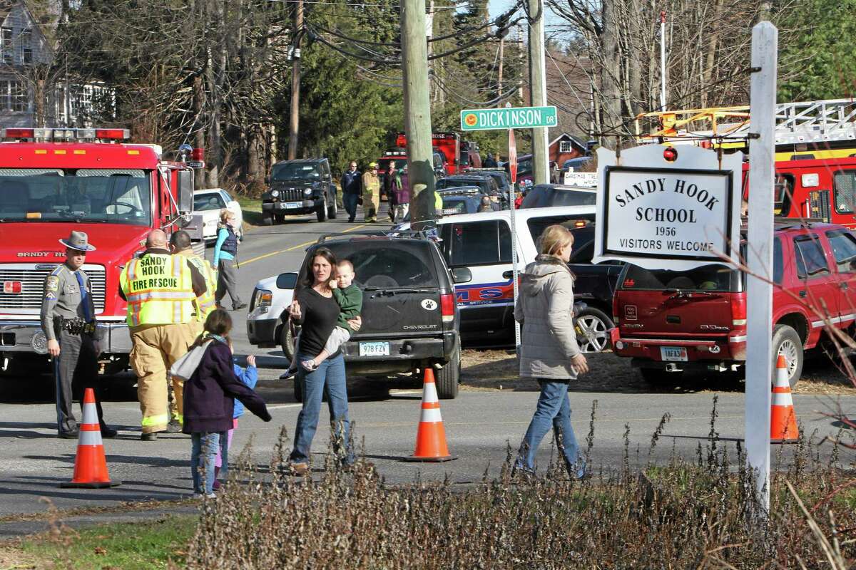 Parents walk away from the Sandy Hook Elementary School with their children following a shooting on Friday, Dec. 14, 2012 in Newtown, Conn. Adam Lanza opened fire inside the Connecticut elementary school where his mother worked killing 26 people, including 18 children, and forcing students to cower in classrooms and then flee with the help of teachers and police.
