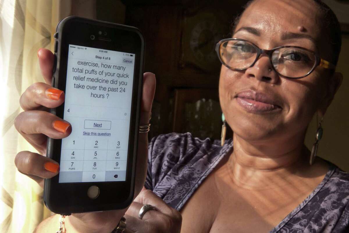 In this July 2, 2015 photo, asthma sufferer Elizabeth Ortiz, who uses the Asthma Health smartphone app daily to track her condition, poses for photos at her apartment, on New York’s Lower East Side. Ortiz measures her lung power each day by breathing into an inexpensive plastic device and then typing the results into the app, which also asks if sheís had difficulty breathing or sleeping, or taken medication that day.
