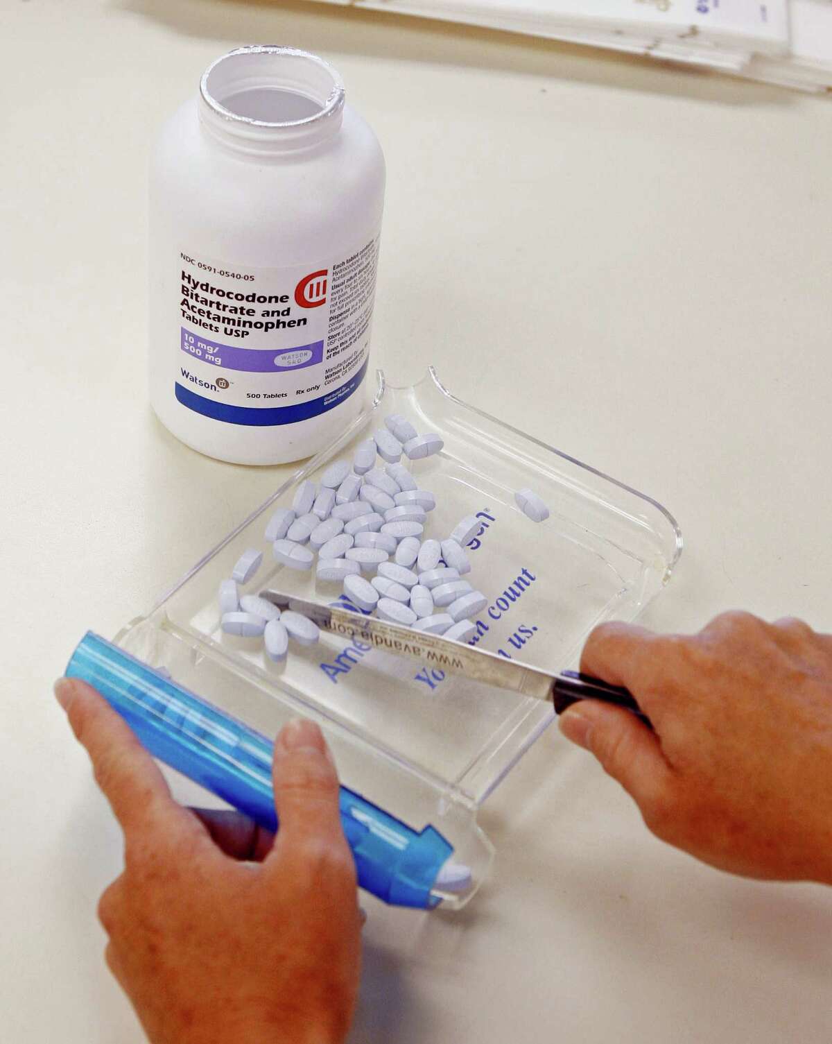 A pharmacy technician poses for a picture with hydrocodone and acetaminophen tablets, also known as Vicodin, at the Oklahoma Hospital Discount Pharmacy in Edmond, Okla.
