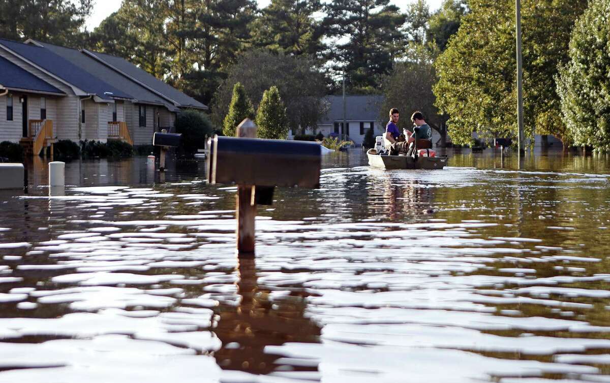 Kyle Hawley, right, and roommate Trey Wood, pilot their boat through the streets of their neighborhood, flooded by water associated with Hurricane Matthew, as they gather belongings from their home on Oct. 12, 2016 in Greenville, N.C.