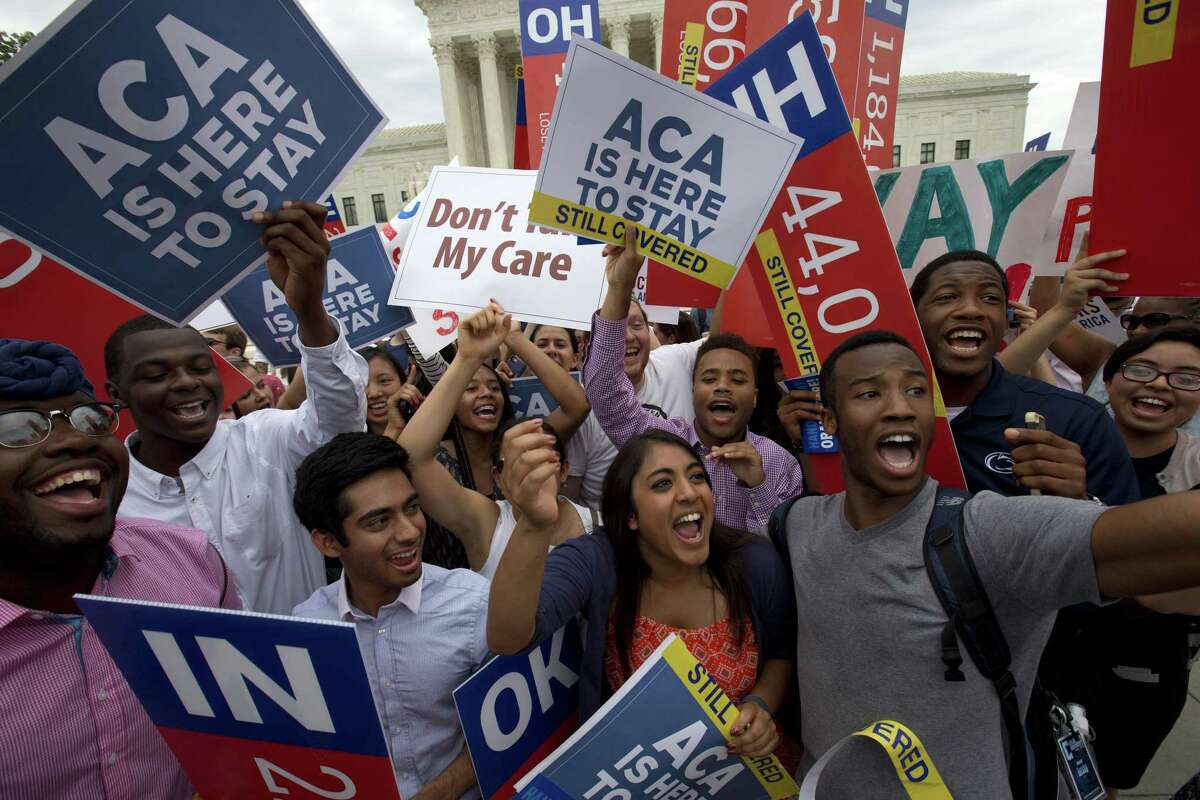 In this June 25, 2015 photo, students cheer as they hold up signs supporting the Affordable Care Act (ACA) after the Supreme Court decided that the ACA may provide nationwide tax subsidies, outside of the Supreme Court in Washington.
