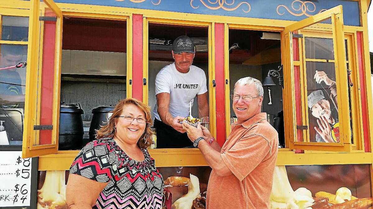 Liz and Buzz Pease of Vernon bought a “poutine,” or french fries and cheese curds topped with a light brown gravy-like sauce, from Mark Smith at one of the food trucks at the Seventh Annual Connecticut Wine Festival at the Goshen Fairgrounds at 116 Old Middle St. in Goshen.