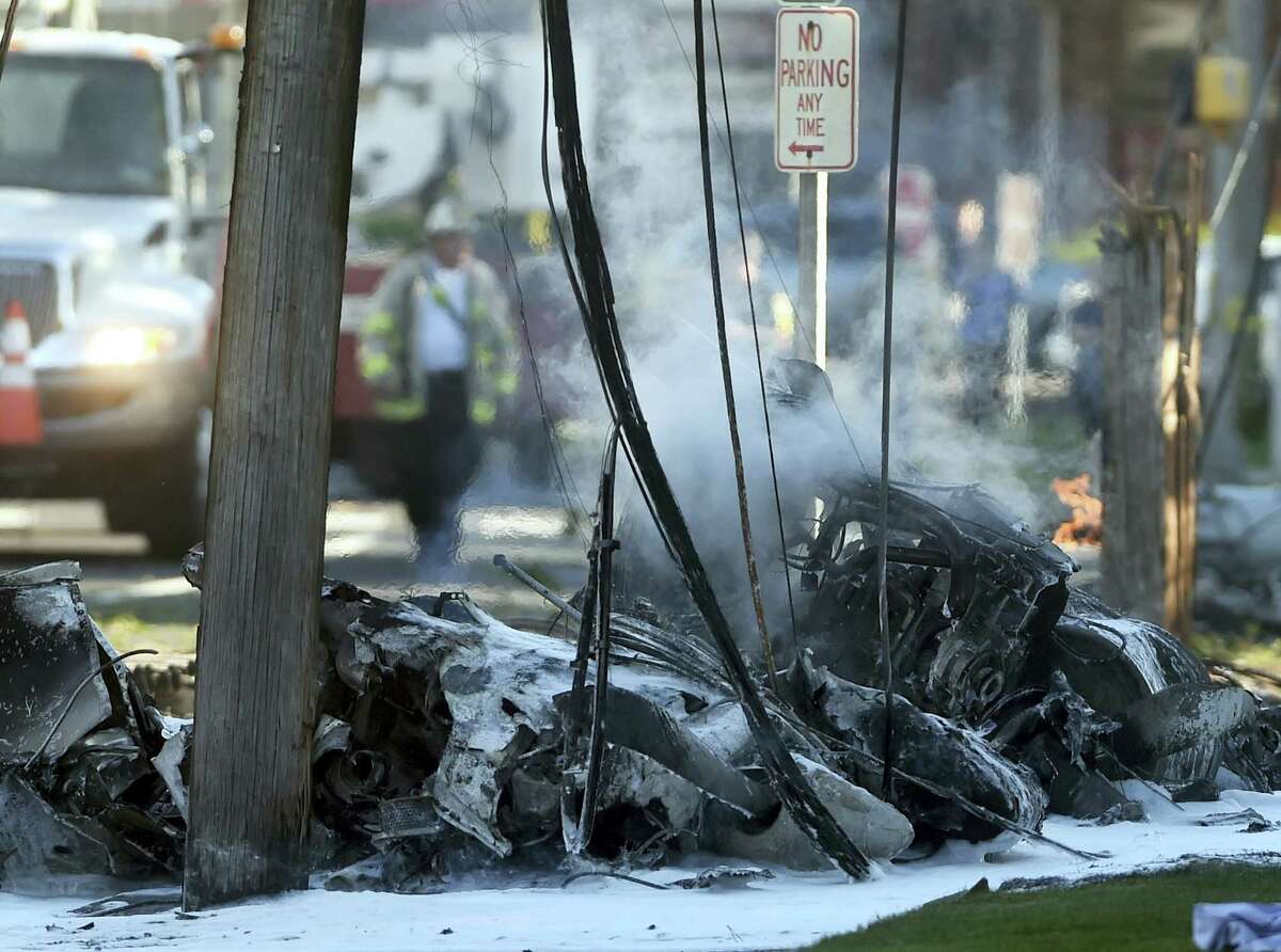 Smoke pours from the smoldering remains of a small plane that crashed on Main Street in East Hartford on Oct. 11.