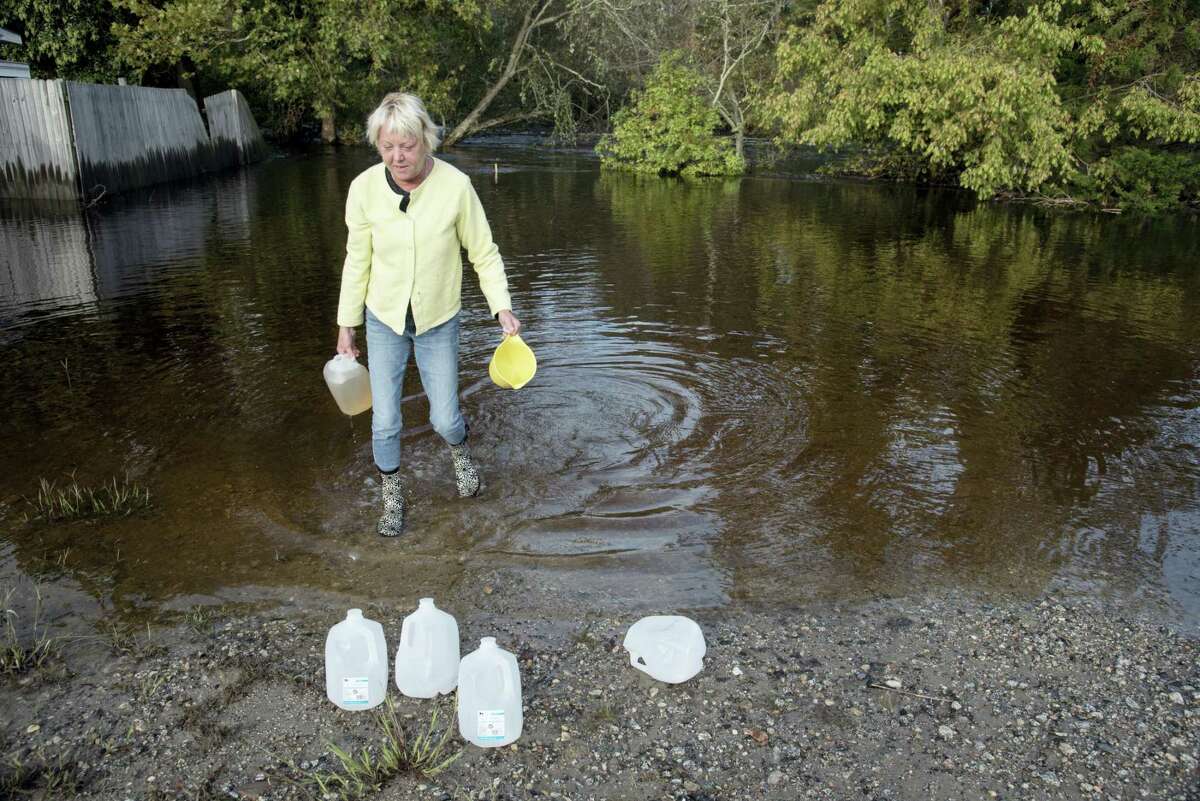 Caroline Kahn collects gallon jugs of water at the foot of 3rd Street in Lumberton, N.C., from floodwaters caused by rain from Hurricane Matthew to use for their plumbing needs Wednesday, Oct. 12, 2016. In North Carolina, tens of thousands of people, some of them as much as 125 miles inland, have been warned to move to higher ground since the hurricane drenched the state.