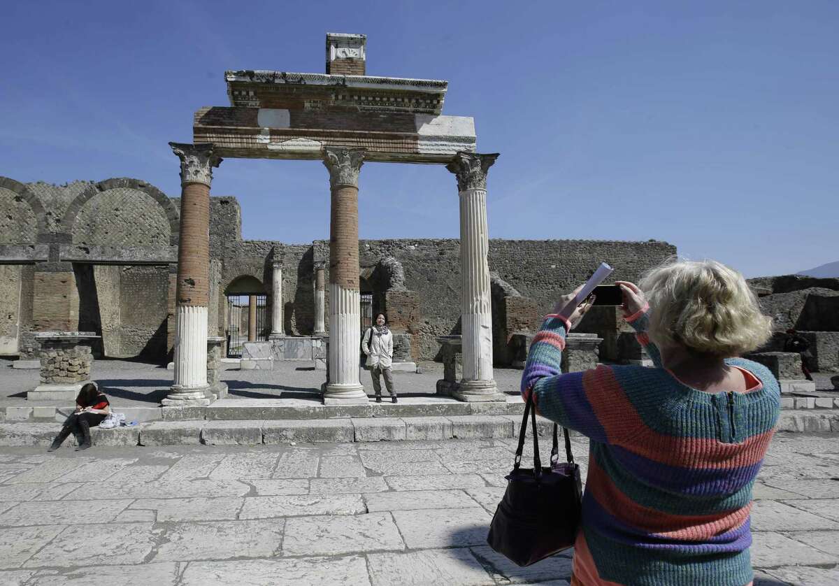 Tourists take pictures at the Pompeii ancient site near the Villa of Mysteries on the occasion of its presentation to journalists in Pompeii, Italy, Friday, March 20, 2015. Italy unveiled the restored crown jewel of the ancient city of Pompeii, the Villa of Mysteries, on Friday, showing off a rare success story as it races to shore up the site that has been marred by such mismanagement that it risked losing EU funding and being delisted as a UNESCO world heritage site. (AP Photo/Gregorio Borgia)
