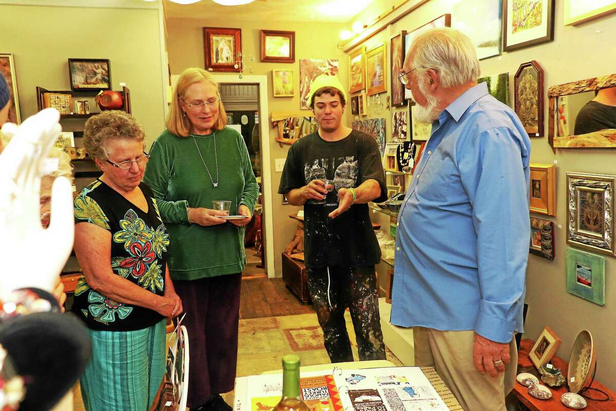 The Artists’ Path has announced it is closing its doors in December. Here Jeff Martin shows his design portfolio during the opening of “Contained” at the Artists’ Path. From left are owner Lori Barker, Fran Clem, Martin and owner Ernie Barker.