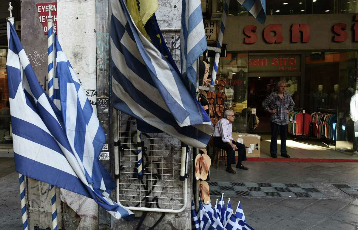 Shop owners wait for customers in Athens on July 23, 2015. Greece’s radical left-led government emerged bloodied but alive early Thursday from a key vote in parliament, which overwhelmingly approved new creditor-demanded reforms despite a revolt among hardliners in the main coalition partner.