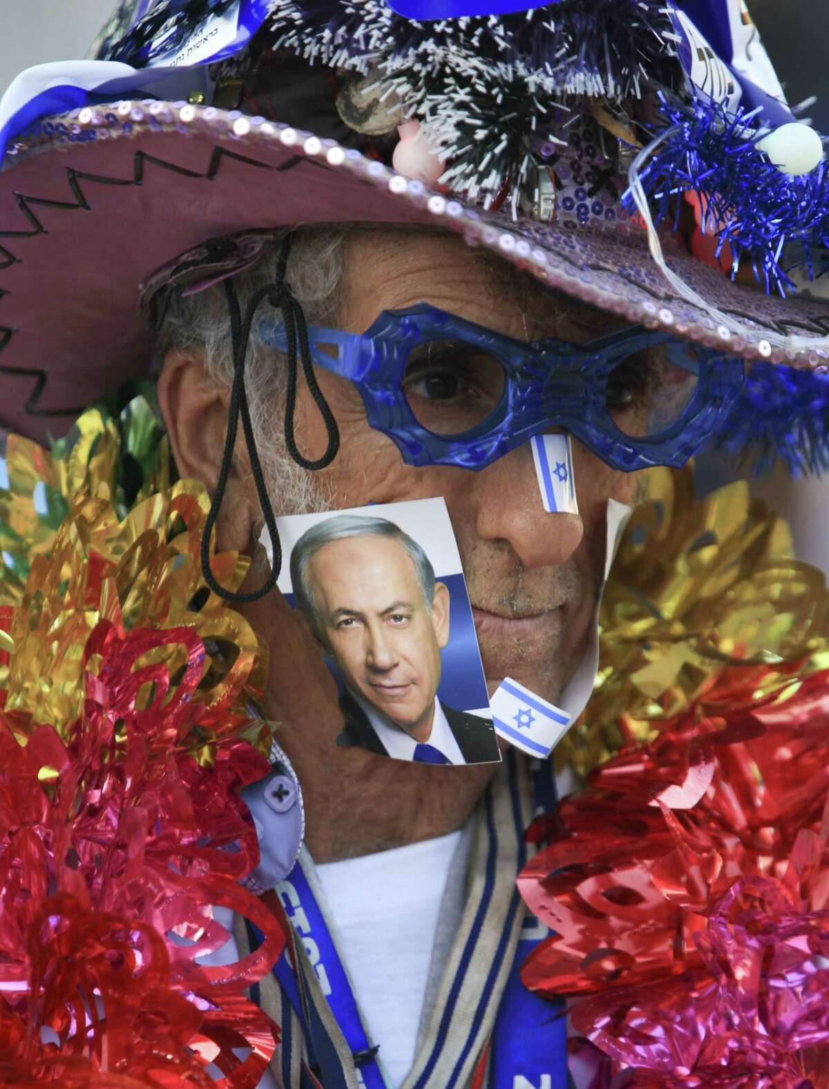 A supporter of Israeli Prime Minister Benjamin Netanyahu, on the photo, waits for his campaign rally to start in Tel Aviv, Israel, Sunday, March 15, 2015, two days ahead of parliament elections. Netanyahu seeks his fourth term as prime minister. (AP Photo/Oded Balilty)