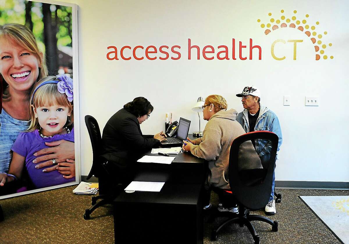 Gildred Ortiz, center and Julio Colon, right, receive help from outreach worker for Access Health CT, Cristela Solorio Ruiz during a grand opening for Connecticut’s health insurance exchange’s first insurance store on Nov. 7, 2013 in New Britain, Conn.