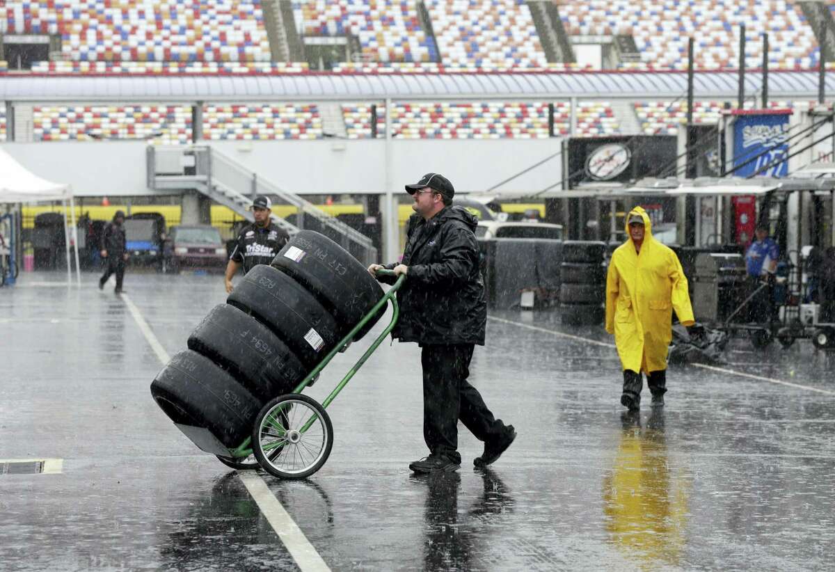 A crew member hauls tires through the NASCAR Xfinity garage in the rain at Charlotte Motor Speedway this past weekend.