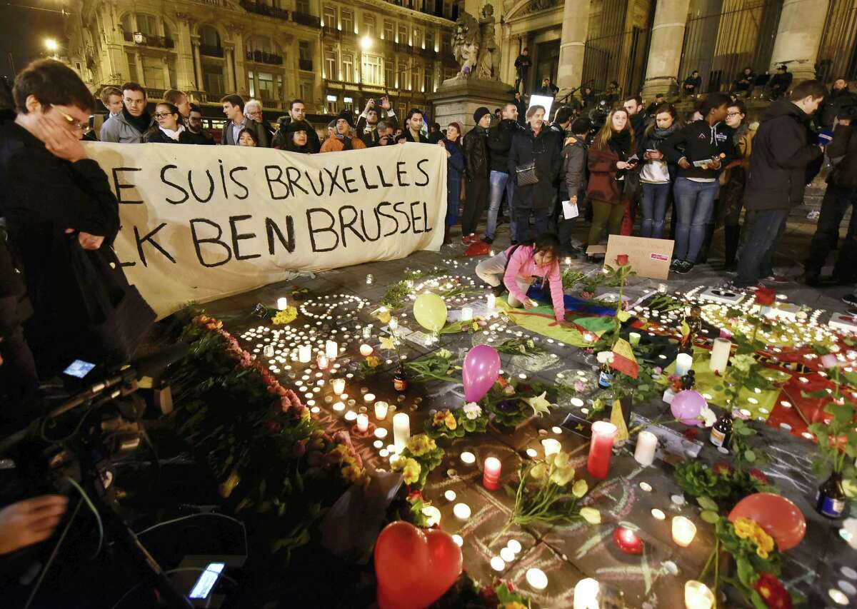 People holding a banner reading “I am Brussels” behind flowers and candles to mourn for the victims at Place de la Bourse in the center of Brussels, Tuesday, March 22, 2016. Bombs exploded at the Brussels airport and one of the city’s metro stations Tuesday, killing and wounding scores of people, as a European capital was again locked down amid heightened security threats.