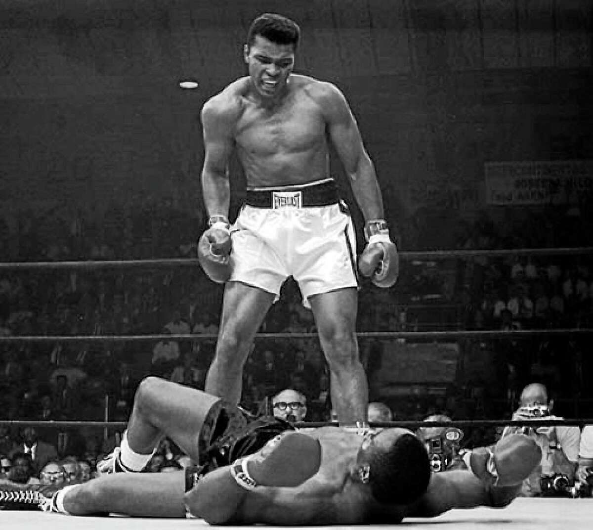 Heavyweight Muhammad Ali defiantly stands over the vanquished Sonny Liston.