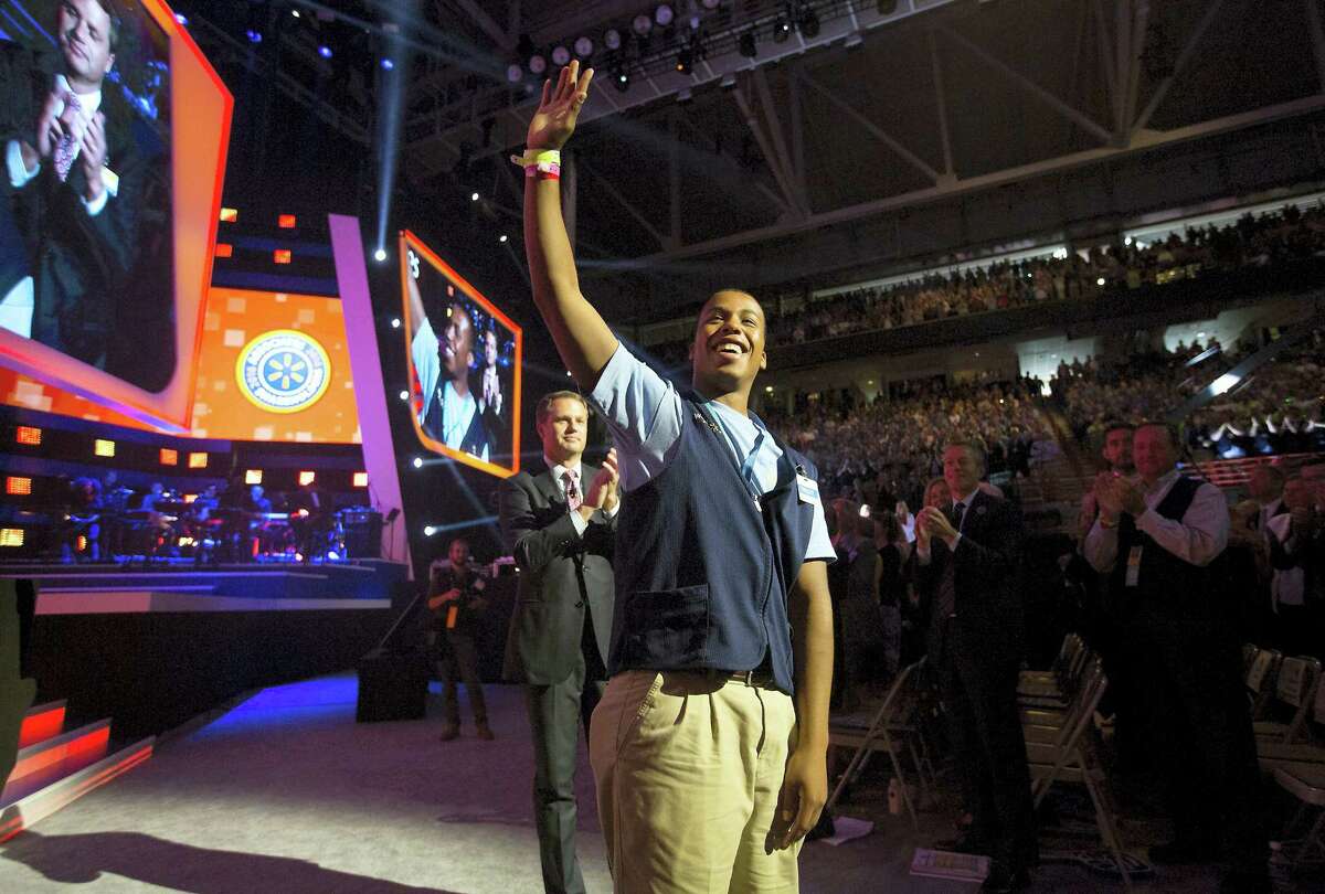 Dwight Blanton acknowledges the crowd’s cheers after being promoted to assistant manager by Doug McMillon, left, Wal-Mart chief executive officer and president, during the annual Wal-Mart Shareholders Meeting Friday in Fayetteville, Ark.