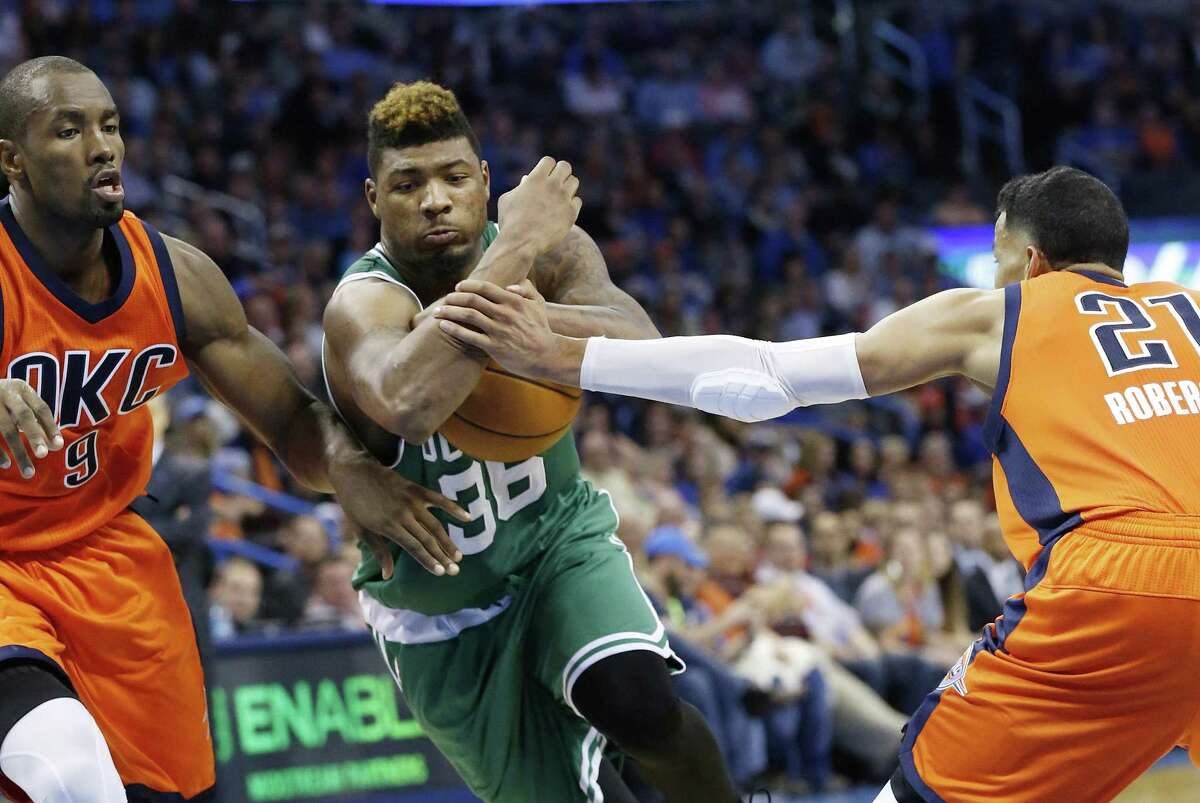Celtics guard Marcus Smart (36) drives between Thunder forward Serge Ibaka and guard Andre Roberson during the third quarter on Sunday.